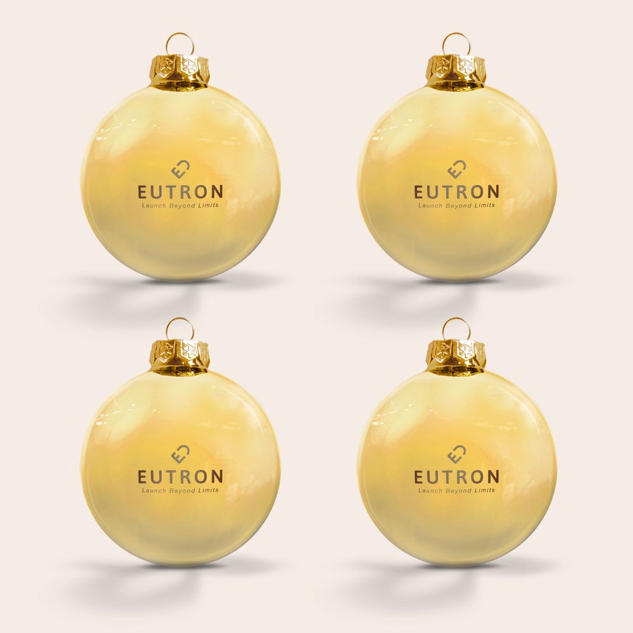 Weihnachtskugel mit Namen Vier goldene Weihnachtskugeln aus Glas, graviert mit dem Text "EUTRON Launch Beyond Limits" und einem Logo.