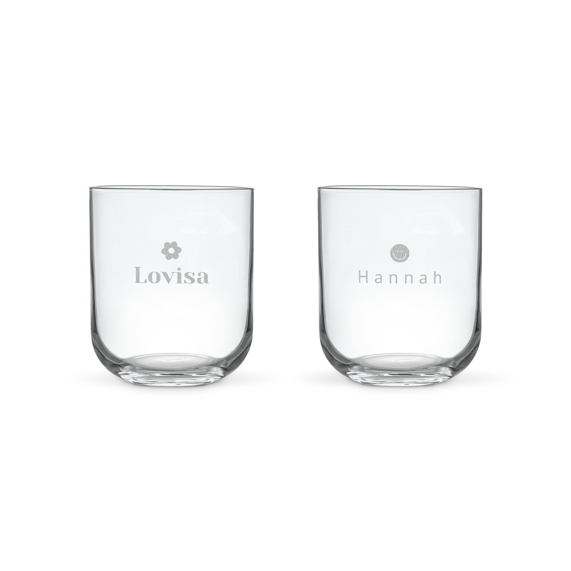 Två personliga vattenglas med namn och symboler, graverade med Lovisa och en blomma samt Hannah och en smiley. Ett glas vatten smakar mycket bättre i ett lyxigt personligt vattenglas