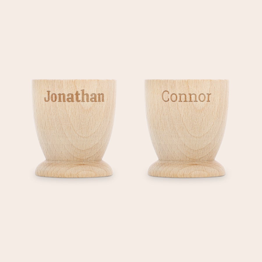 Ceașcă personalizată pentru ouă Două cupe pentru ouă personalizate din lemn de fag, gravate cu numele Jonathan și Connor, ideale pentru un mic dejun memorabil.