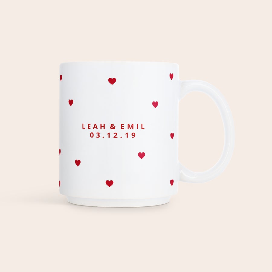 Stabelbare krus med bilde Stablebart fotokrus med navnene "LEAH & EMIL" og datoen "03.12.19" trykt i rødt, omringet av røde hjerter på en hvit bakgrunn.