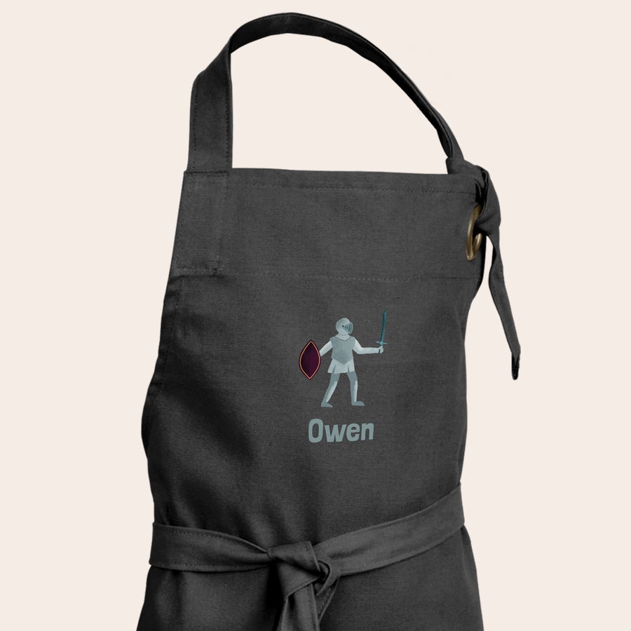 Delantal infantil personalizado Delantal infantil negro impreso con un dibujo de caballero y el nombre "Owen" para un delantal personalizado.