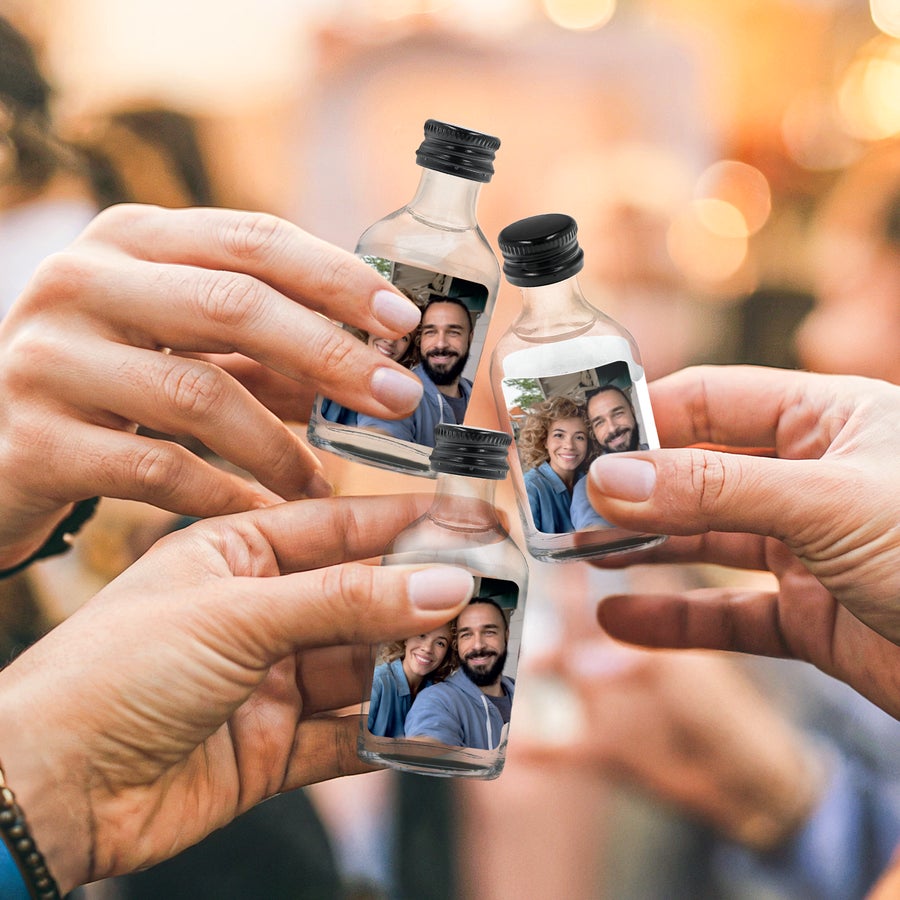 Mini flesjes drank personaliseren Drie handen proosten met Mini Vodka flesjes, gepersonaliseerd met een foto van een lachend stel.