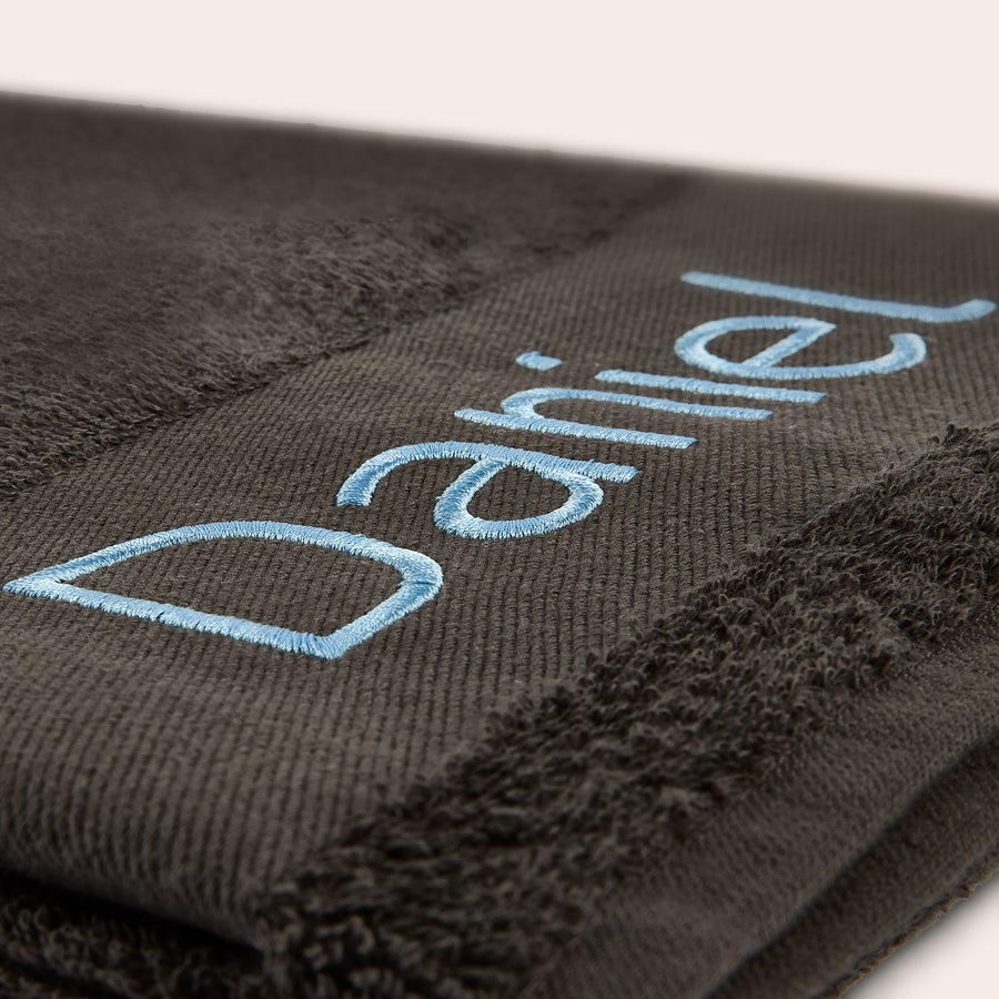 Badetuch mit Namen Personalisiertes anthrazitfarbenes Handtuch mit dem Namen Daniel in Hellblau bestickt