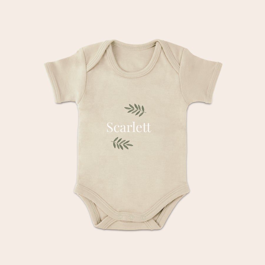 Body med eget tryck Beige personlig babybody med eget tryck av namnet Scarlett och gröna löv på framsidan