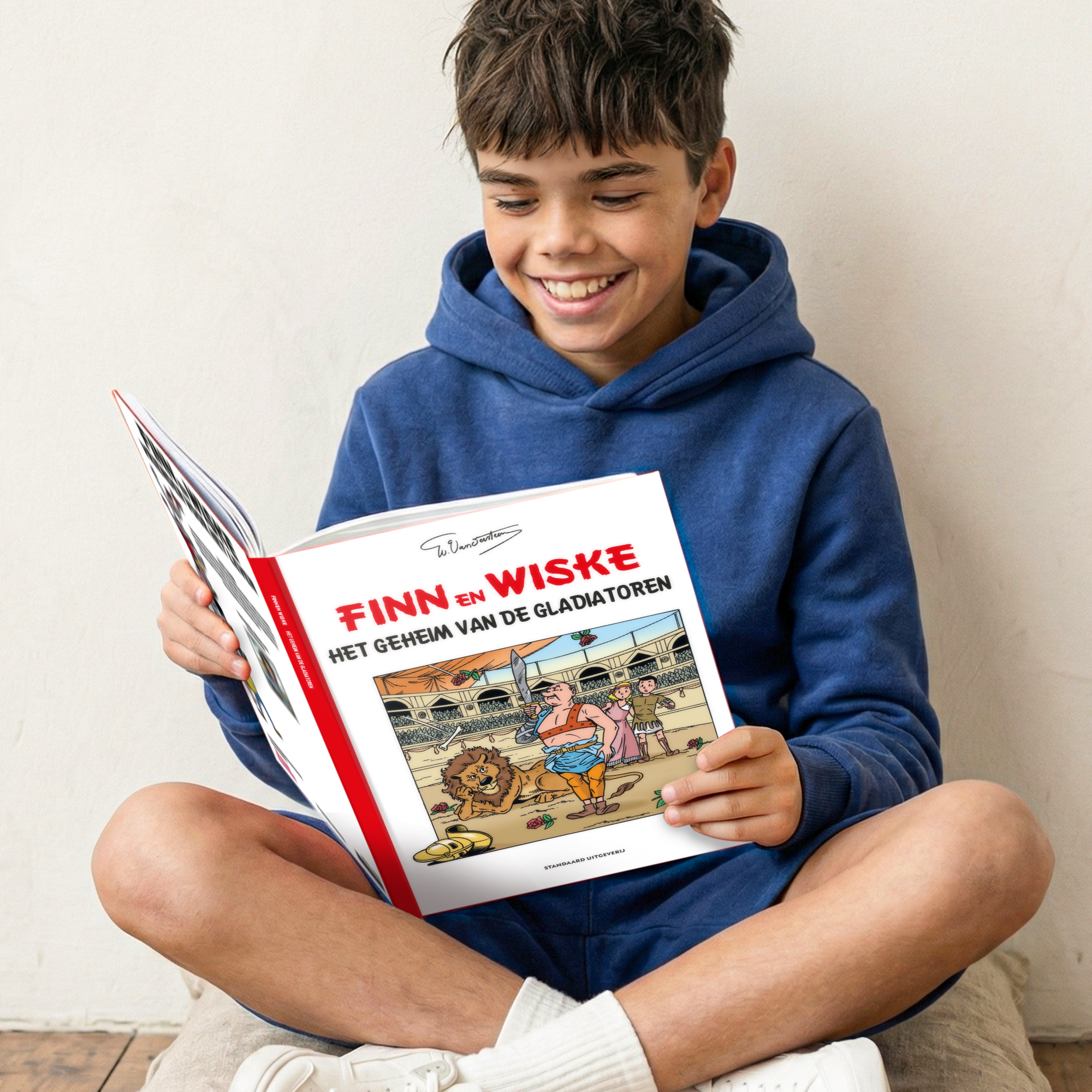 Persoonlijk stripboek Suske en Wiske 'Het geheim van de gladiatoren' (Hardcover) met de naam 'Finn' op de voorkant gedrukt, gelezen door een glimlachende jongen.
