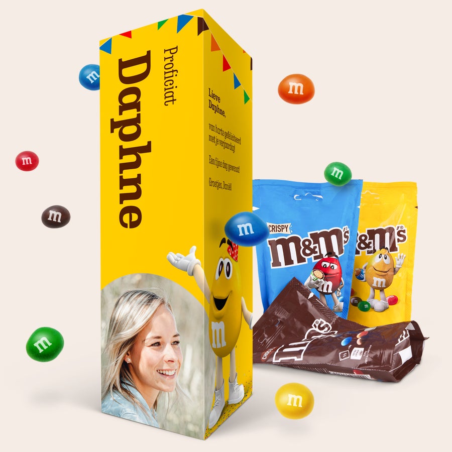Gepersonaliseerd M&M's cadeaupakket Gepersonaliseerd M&M's cadeaupakket met een foto, naam 'Daphne' en persoonlijke tekst 'Proficiat' geprint op een gele geschenkdoos.