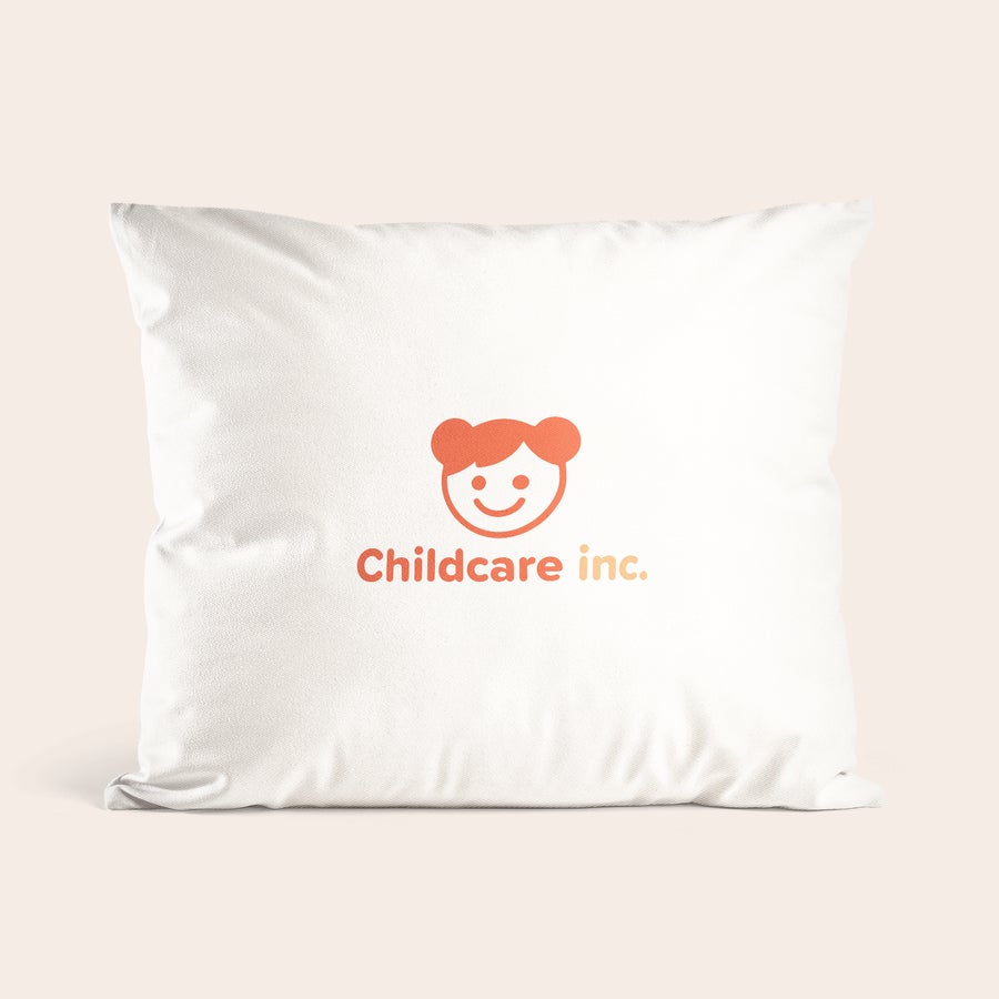 Přizpůsobené tištěné polštáře Bílý polštář s potiskem loga "Childcare inc." a oranžovým obličejem. Personalizovaný polštář s textem a fotografií.