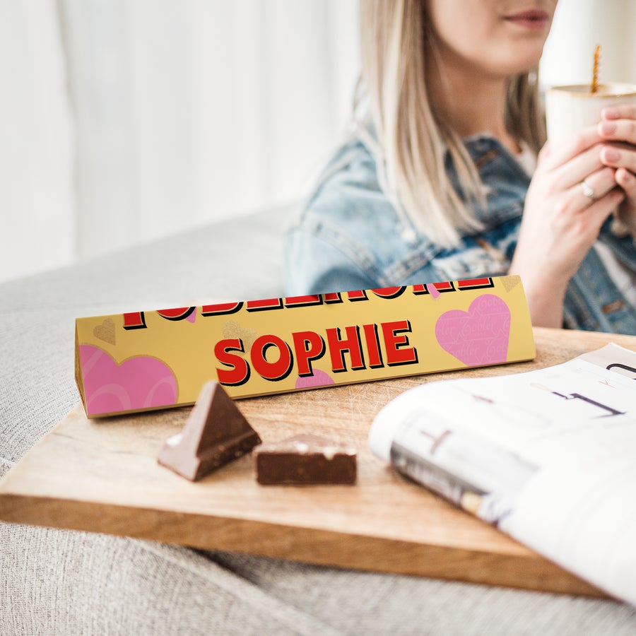 Toblerone Liebe Personalsieren Personalisierte Toblerone mit Name Sophie auf der Verpackung, gedruckt mit rosafarbenen Herzen und goldfarbenen Akzenten.