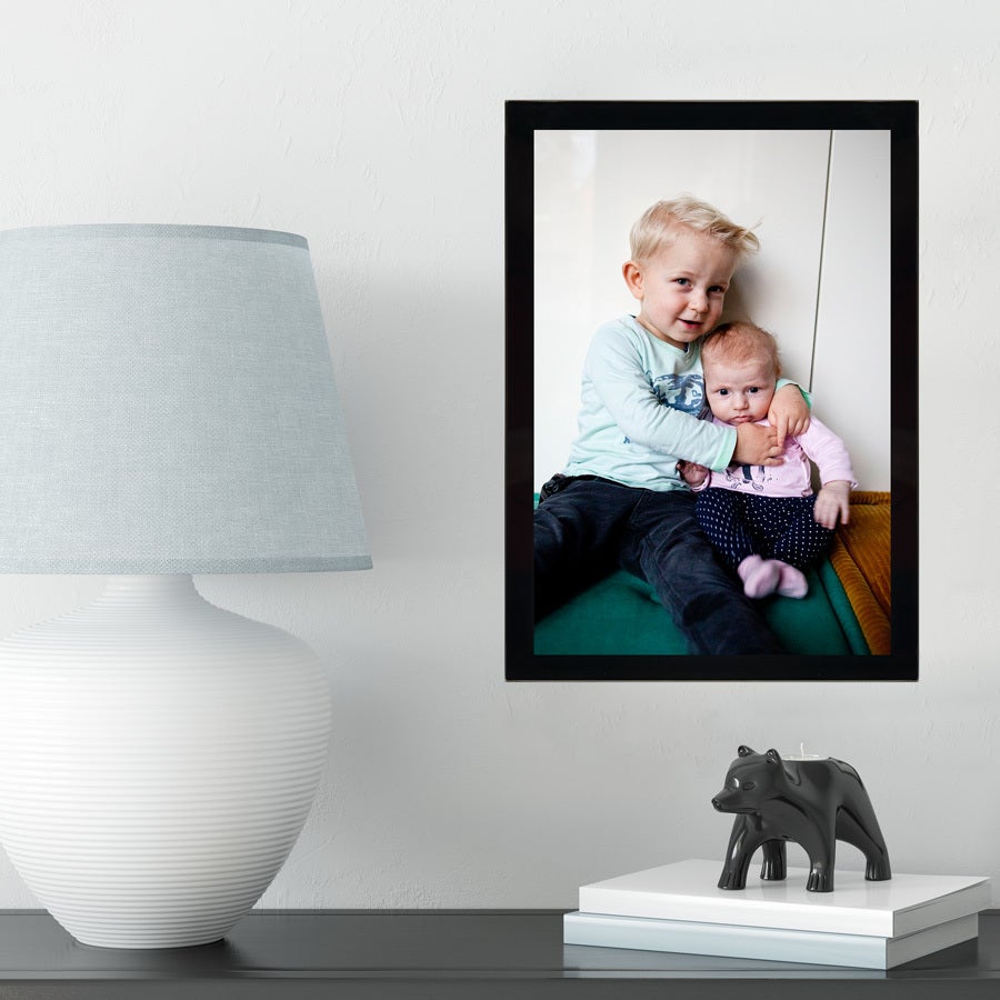 Fotoramme i glass med svart kant og et bilde av to barn for å gjenoppleve minner.