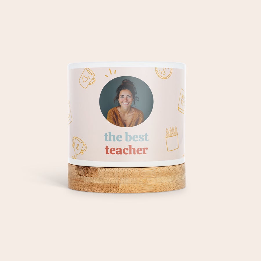Maceta personalizada Maceta de cerámica blanca personalizada, impresa con la foto de una mujer sonriendo y el texto "the best teacher", sobre base de bambú para regálales vegetación.