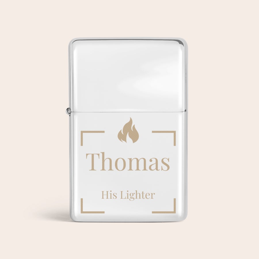 Sytkärit kaiverruksella Hopeinen kaiverrettu nimisytytin Thomas ja His Lighter -tekstillä, liekkikuviolla ja kulmiin sijoitetuilla L-muodoilla.