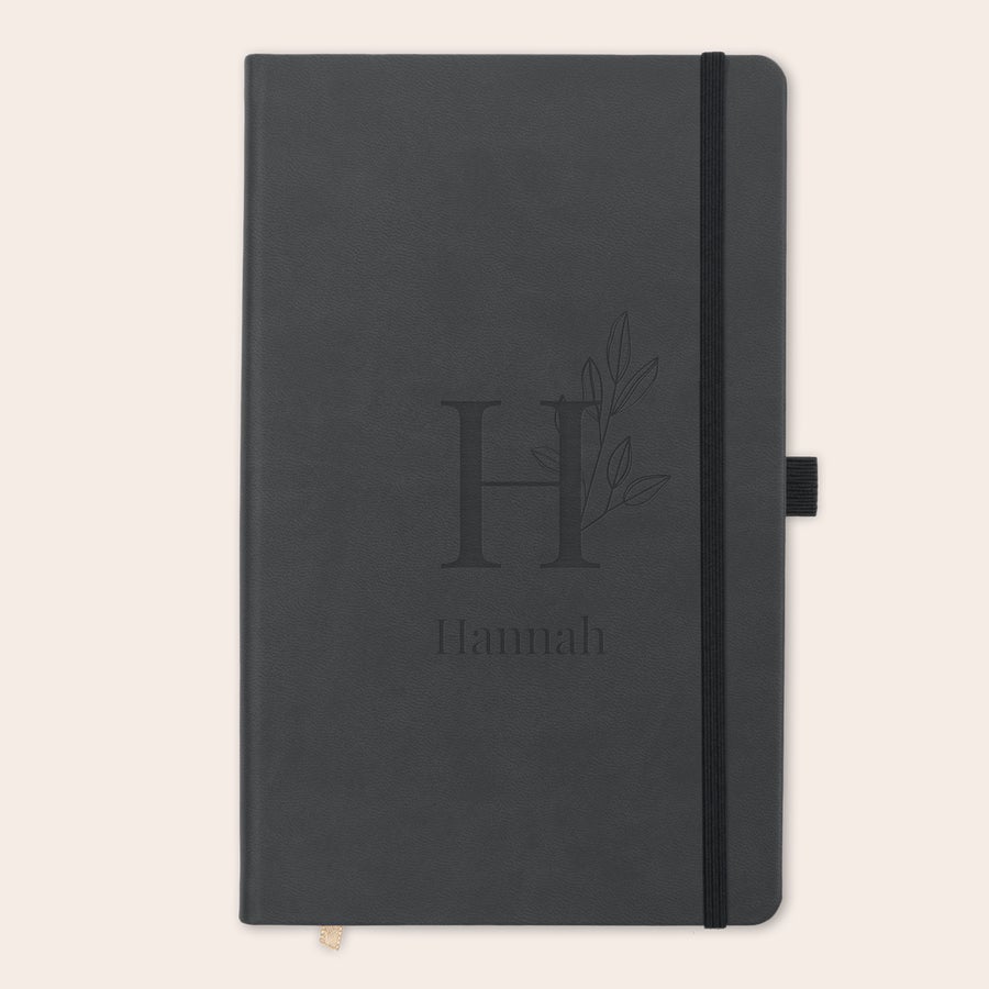 Notitieboek met naam Gegraveerd notitieboekje met letter H, bloemdecoratie en naam Hannah op de zwarte kaft.