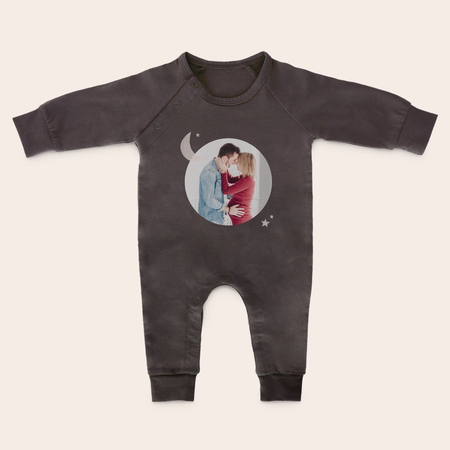 Baby lekedrakt med trykk En mørkegrå sparkedress med trykt bilde av et par med en gravid kvinne, omringet av en måne og stjerner.