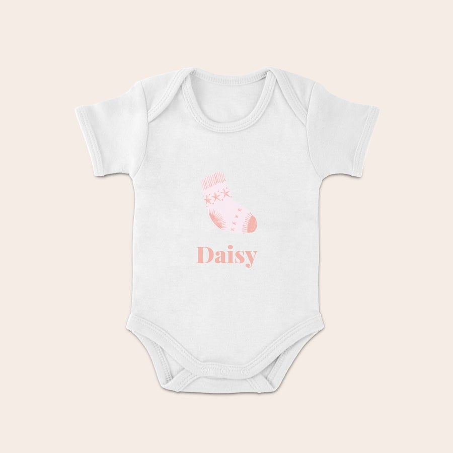 Barnets första Jul-babybody Vit julbyxa med en rosa julstrumpa och namnet "Daisy" tryckt i rosa under. Perfekt att fira ditt barns första jul.