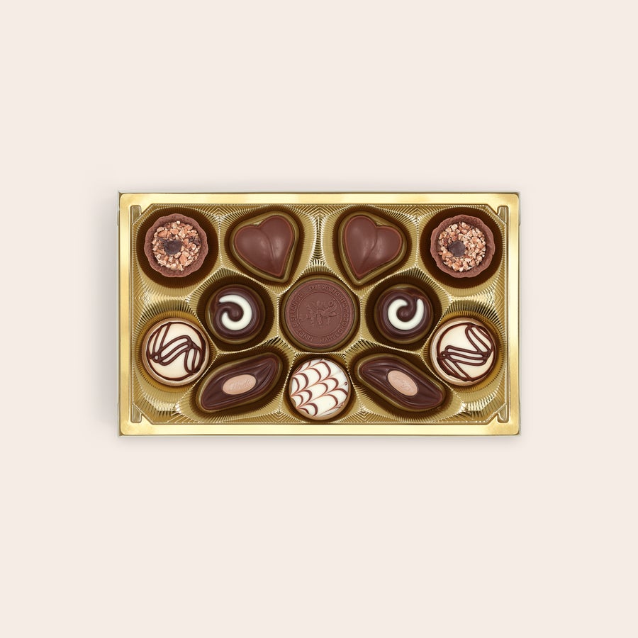 Lindt pralines Classic Open doos met gouden vakjes vol diverse Lindt-pralines, voor een blijvende herinnering.