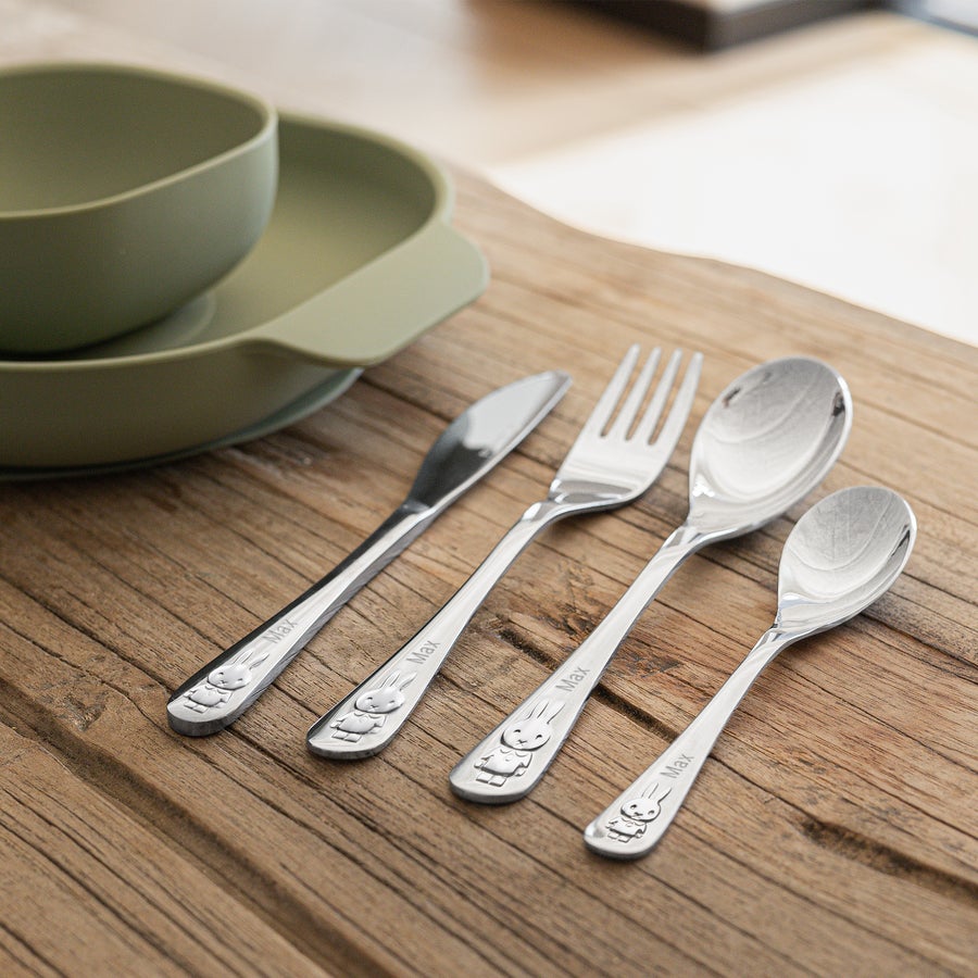 nijntje kinderbestek graveren Zilverkleurig nijntje bestek, met de naam Max gegraveerd, naast een mintgroene kom op een houten tafel.