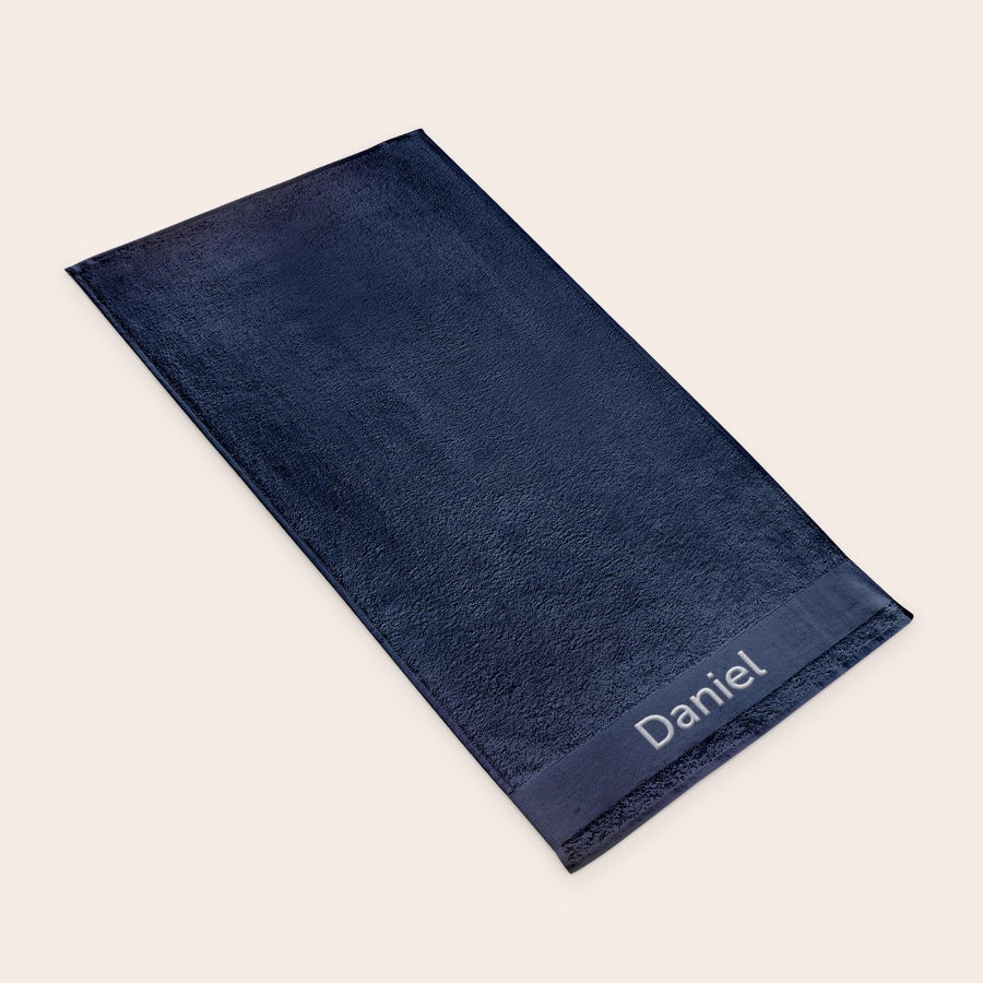 Prosop de baie cu text Prosop albastru de baie personalizat cu numele Daniel brodat elegant cu ață albă.