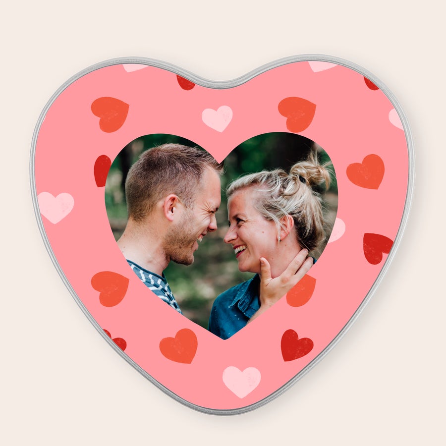 Cutie de tablă personalizată Cutie de tablă roz în formă de inimă, personalizată cu o fotografie a unui cuplu, înconjurată de inimi roșii.