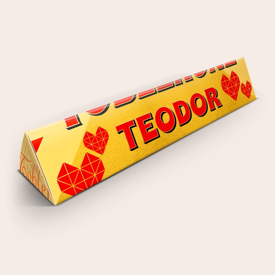 Toblerone med namn och foto Gul Toblerone med personligt omslag, tryckt med namnet Teodor i rött och röda hjärtan.