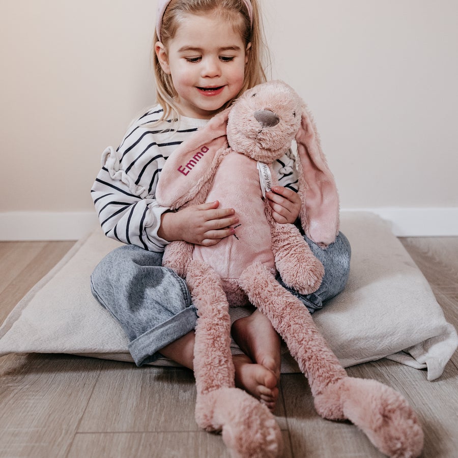 DouDou personalizado para bebê - Happy Horse Coelho Richie de pelúcia rosa, com nome bordado Emma, abraçado por uma criança sorridente.