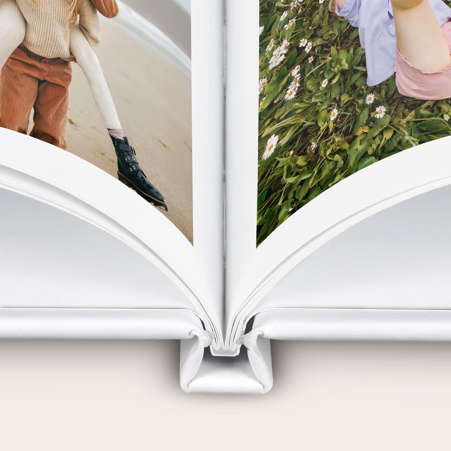 Fotobuch gestalten Aufgeschlagenes personalisiertes Fotoalbum mit Fotos eines Kindes am Strand und eines Kindes im Gras bedruckt.