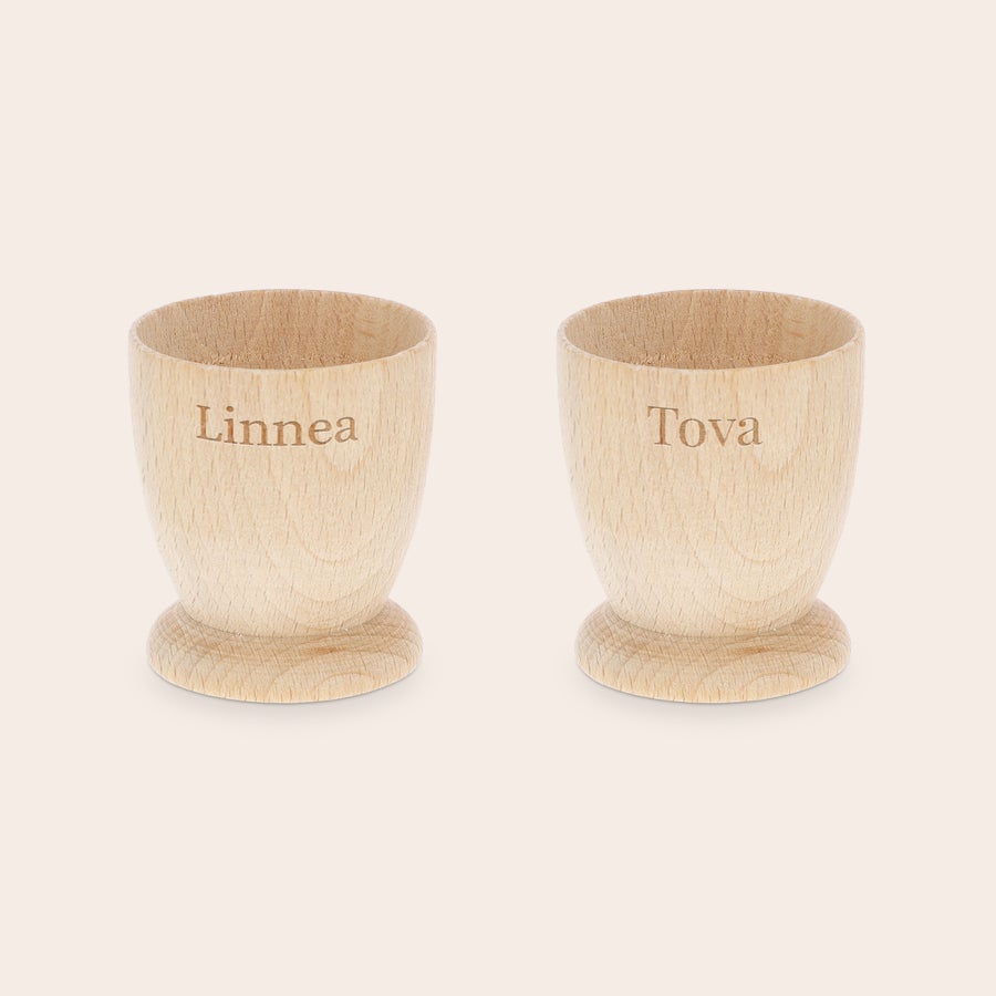 Personifierad äggkopp Två personliga äggkoppar i ljust bokträ, graverade med namnen Linnea och Tova. Gör frukosten minnesvärd med personliga äggkoppar.