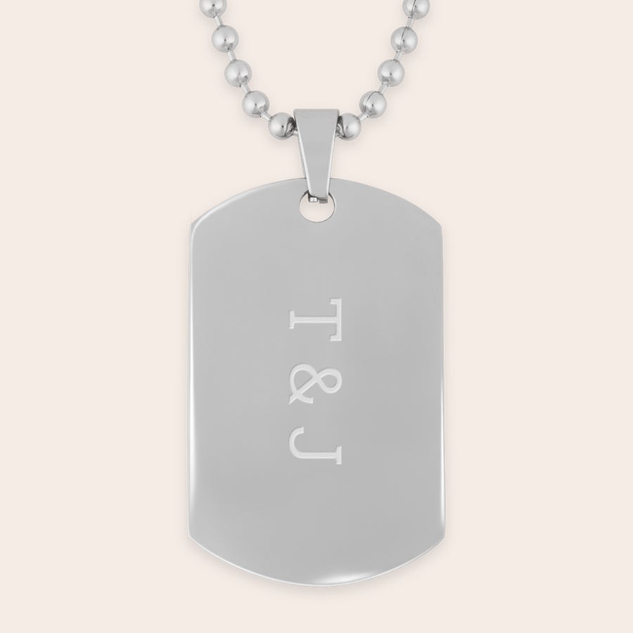 Dog Tag mit Gravur Glänzendes Dog Tag mit Gravur, der die Initialen T & J zeigt, an einer Kette.