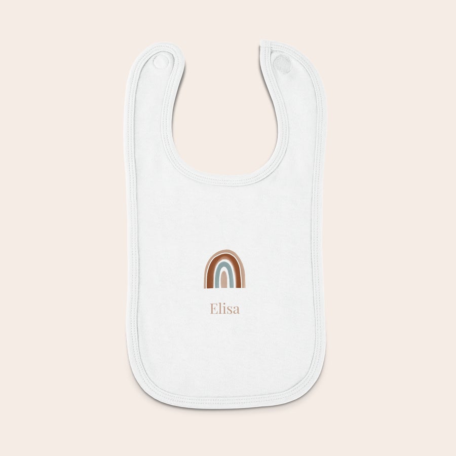 Baby bib Hvit personlig babybib med navn Elisa trykket under et brunt og blått regnbuemotiv.