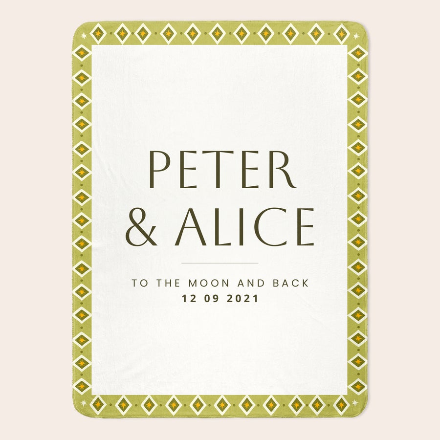 Fleece-torkkupeitto painatuksella Uniikki pehmoinen torkkupeitto vihreällä geometrisella reunuksella, johon on painatettu nimet Peter & Alice ja teksti "To the moon and back 12 09 2021"