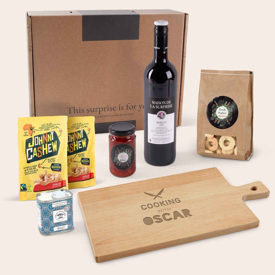 Darčekový balík s vínom, občerstvením a drevenou servírovacou doskou Luxusné balenie s gravírovanou servírovacou doskou pre Oscara, vínom Merlot, orieškami a občerstvením.