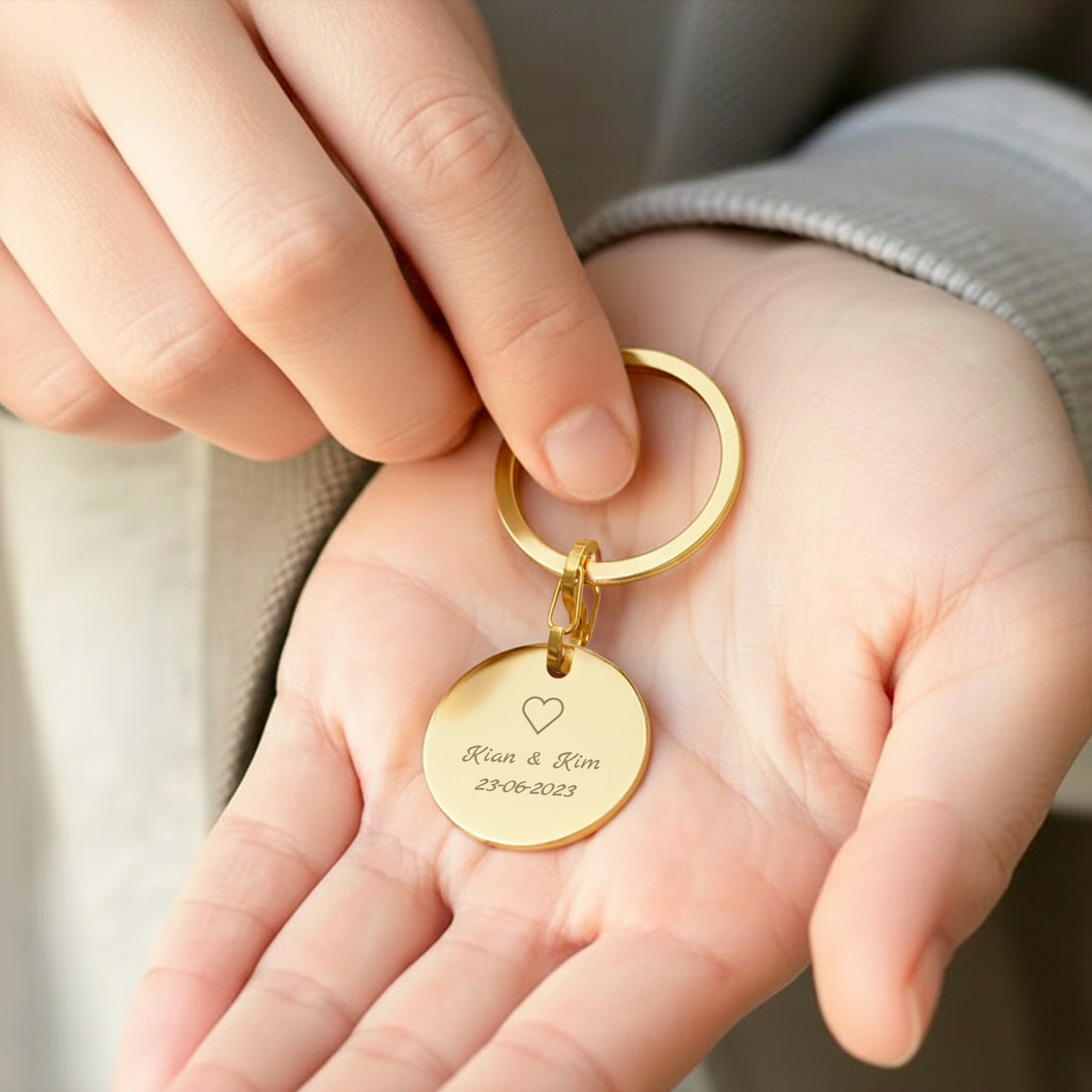 Schlüsselanhänger mit Gravur - Rund - Gold, personalisiert mit Namen und Datum, gehalten in offener Hand