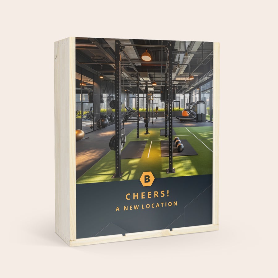Personlig Riondo Prosecco med glas Personlig vinlåda i trä med en flaska Riondo Prosecco, anpassad med ett tryckt foto av ett gym och texten Cheers! A New Location.