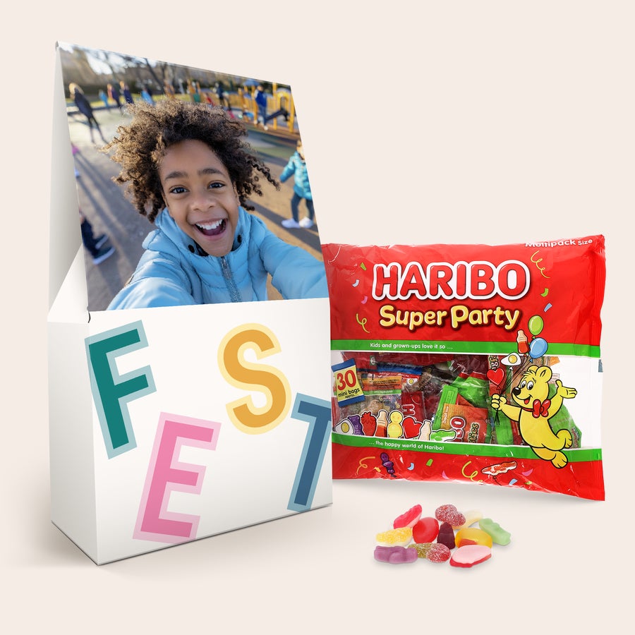 XL-Haribo-Geschenkbox Personalisierte XL-Haribo-Geschenkbox mit einem Foto eines lachenden Kindes und dem Schriftzug FEST, dazu ein Beutel Haribo Super Party.