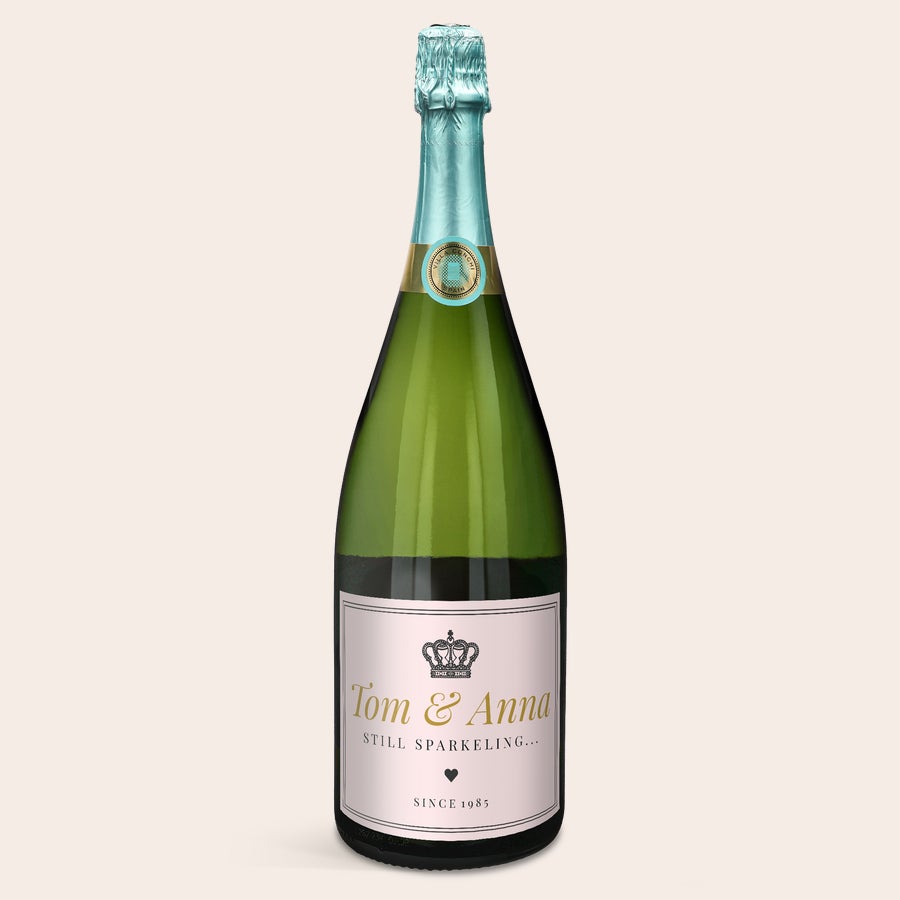 Cava Villa Conchi Cava Villa Conchi Magnum pezsgő üveg, személyre szabott címkével, Tom & Anna nevekkel és 1985-ös évszámmal, királyi koronával és szívvel díszítve. Ki fog lepni egy üveg Cava Villa Conchi - Magnum címkével?