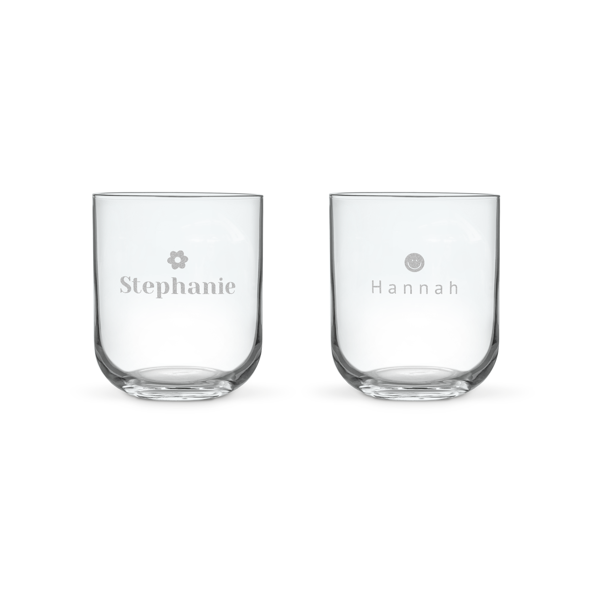 Two personalized water glasses, one engraved with the name Stephanie and a flower, the other with Hannah and a smiley face.