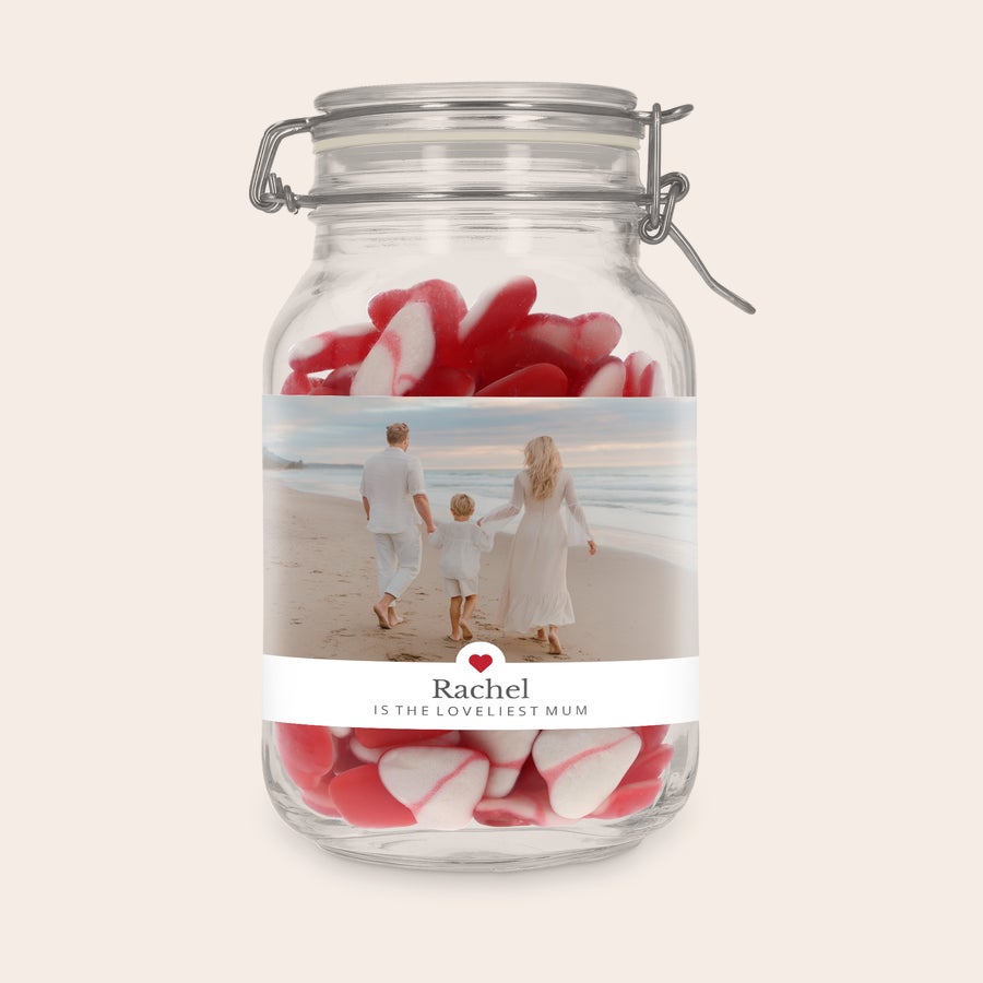 Personalised sweet jar Glass jar with a personalized photo label of a family on a beach, filled with red and white heart-shaped sweets. The label reads Rachel is the Loveliest Mum.