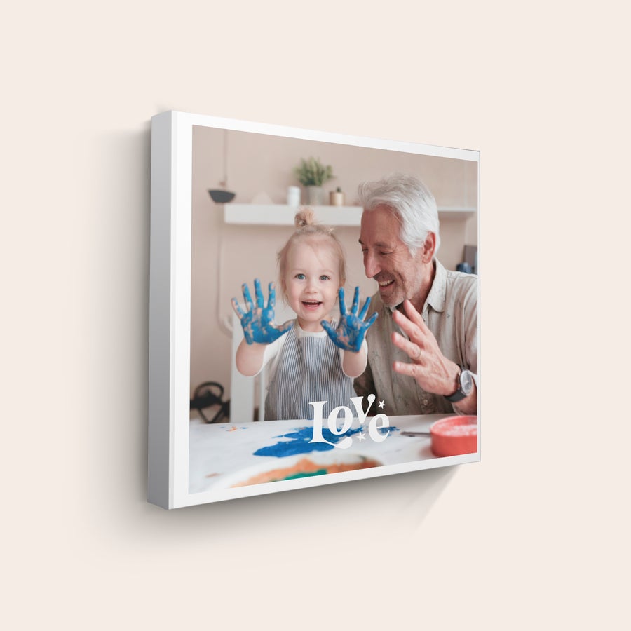 Foto auf Leinwand Leinwand mit Foto, auf der ein Opa mit einem lachenden Mädchen abgebildet ist, das blaue Farbe an den Händen hat.