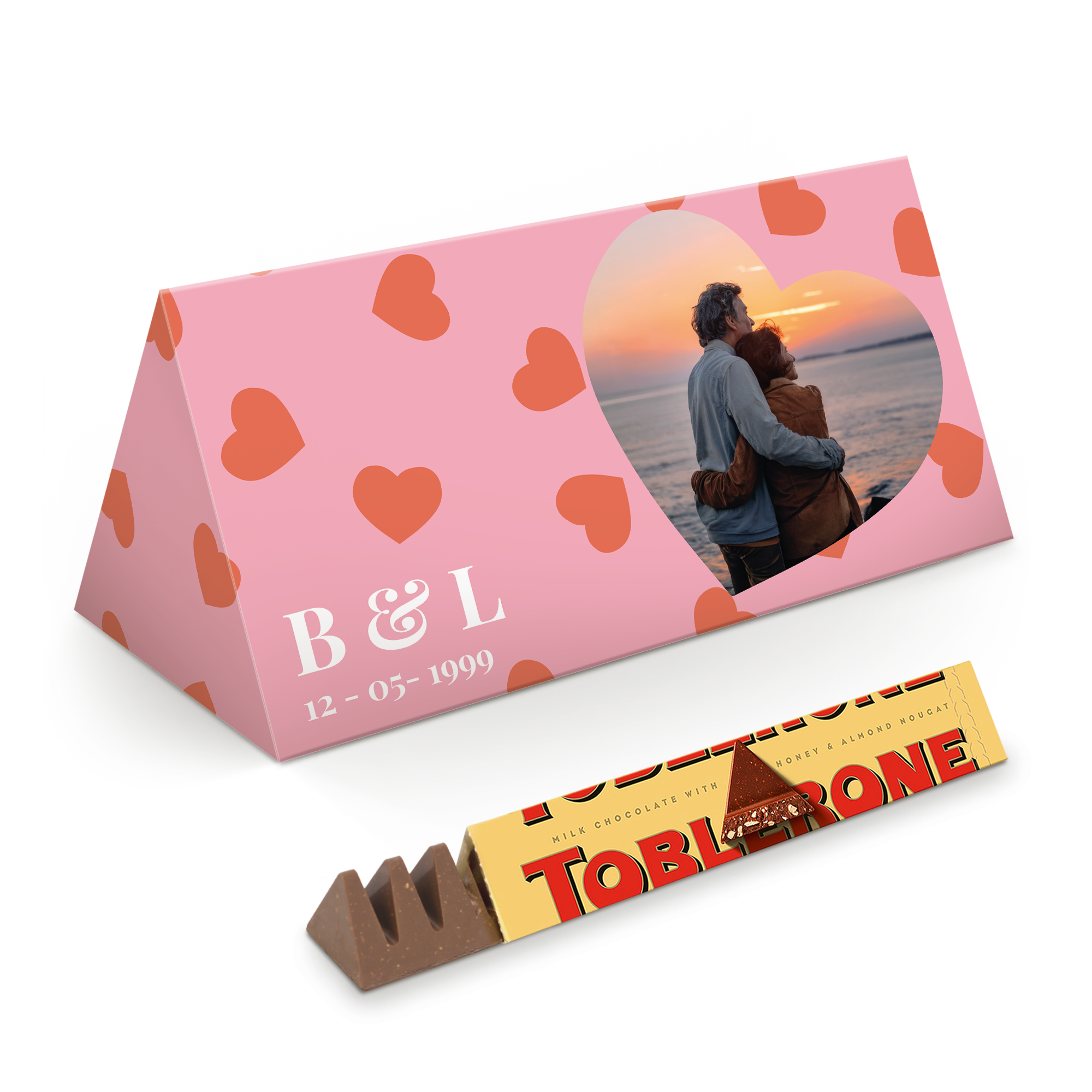 Ambalaj roz personalizat cu o inimă pentru o fotografie, inițialele B & L și data 12-05-1999, alături de o ciocolată Toblerone XL desfăcută.