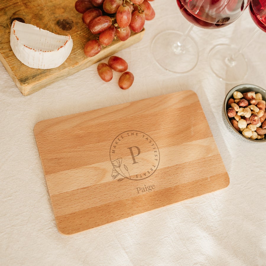 Tagliere in Legno Personalizzato Tagliere in legno personalizzato con testo inciso "Paige Makes the Tastiest Treats" con iniziale P e decorazione floreale.