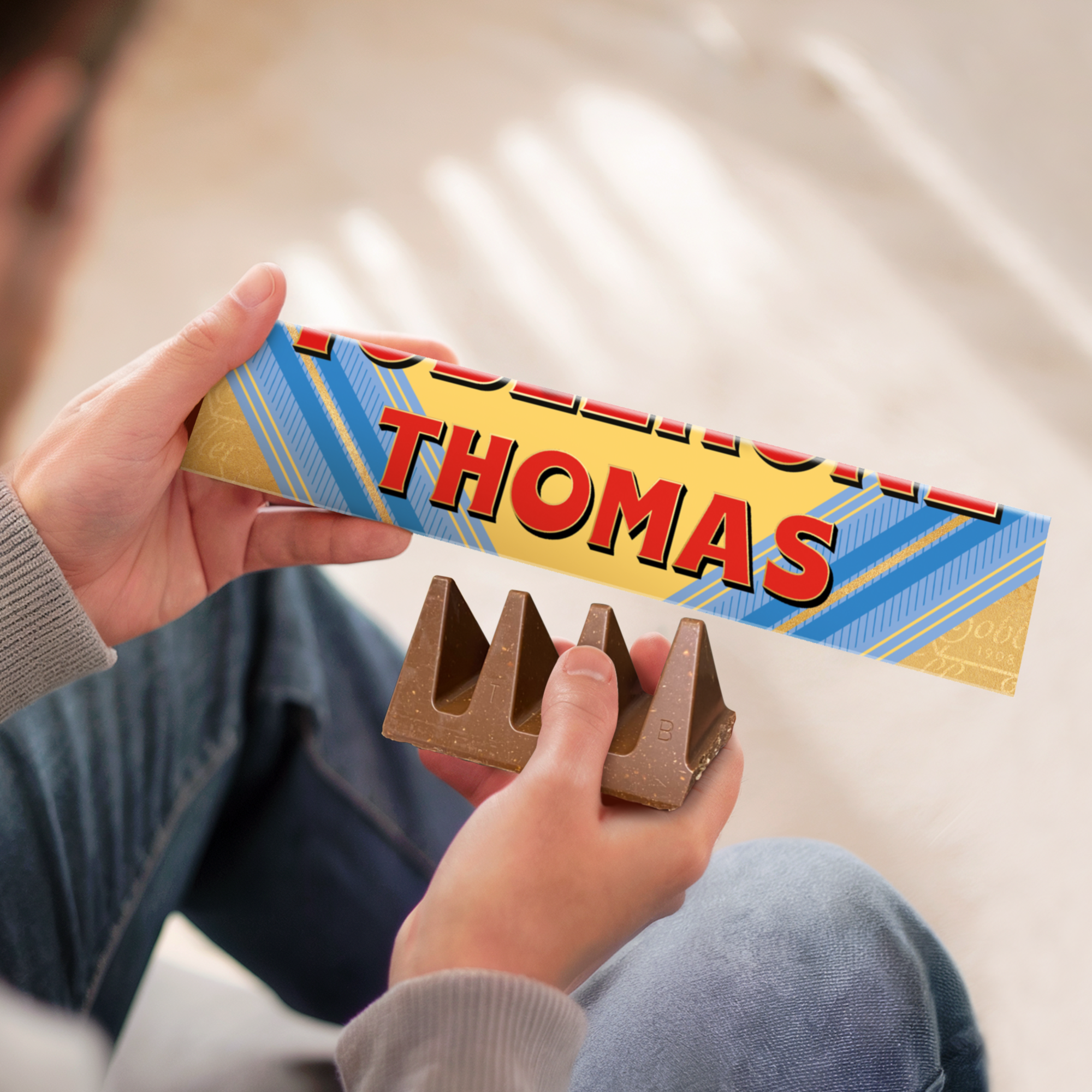 En personaliserad Toblerone med Thomas tryckt på omslaget och en Toblerone chokladbit i handen.