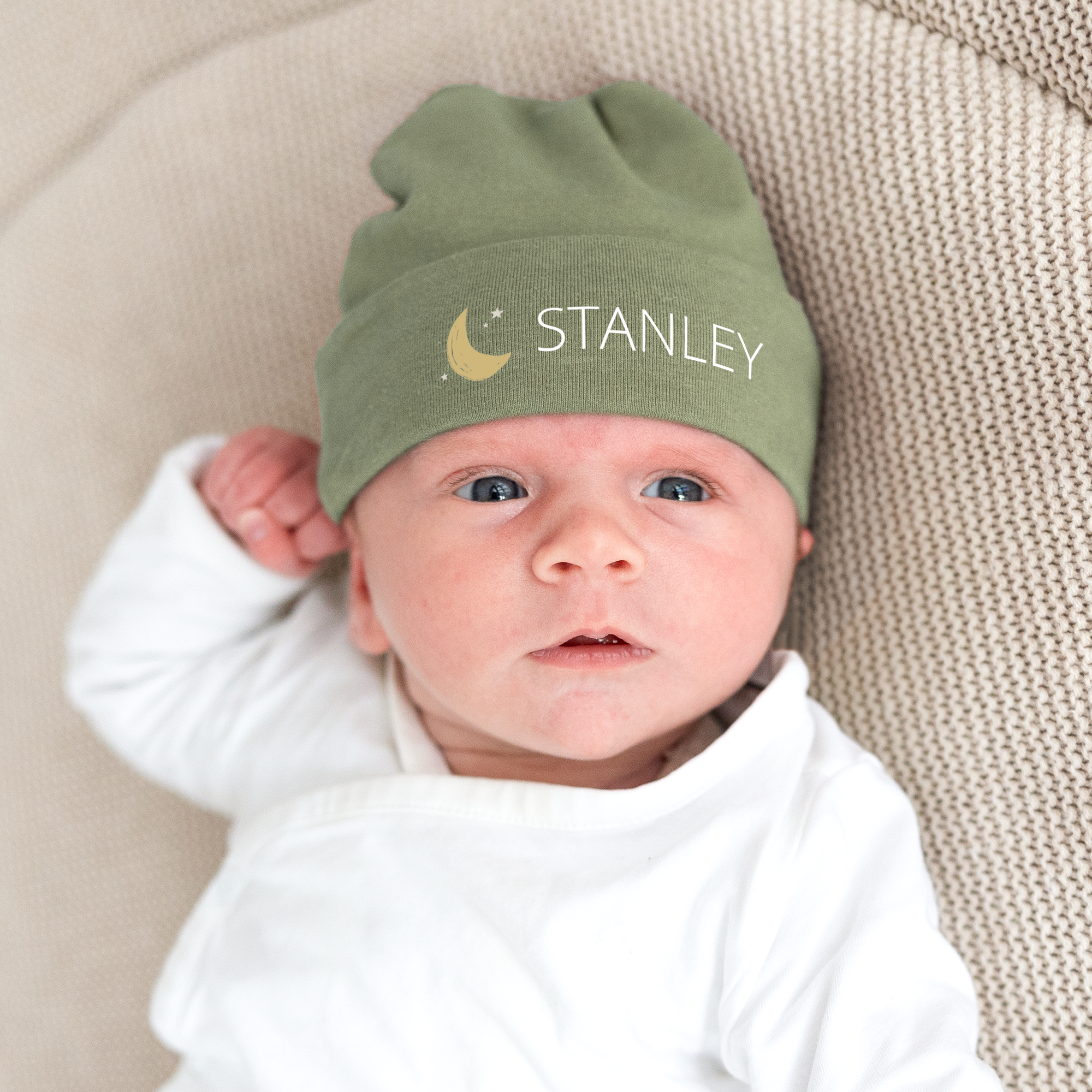 Bebé com gorro personalizado verde azeitona, com o nome Stanley e um desenho de lua impressos