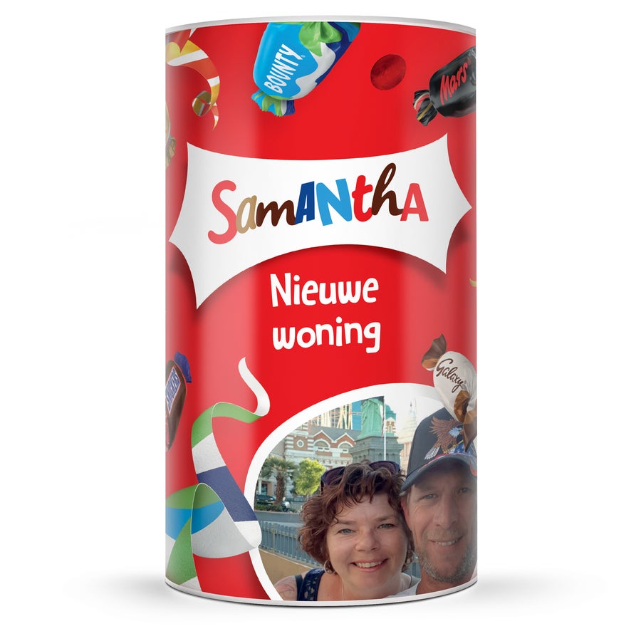 Celebrations XL chocolade cadeauverpakking met naam en foto Rode Celebrations tube bedrukt met naam Samantha, tekst Nieuwe woning en een foto van een stel, versierd met papieren slingers.