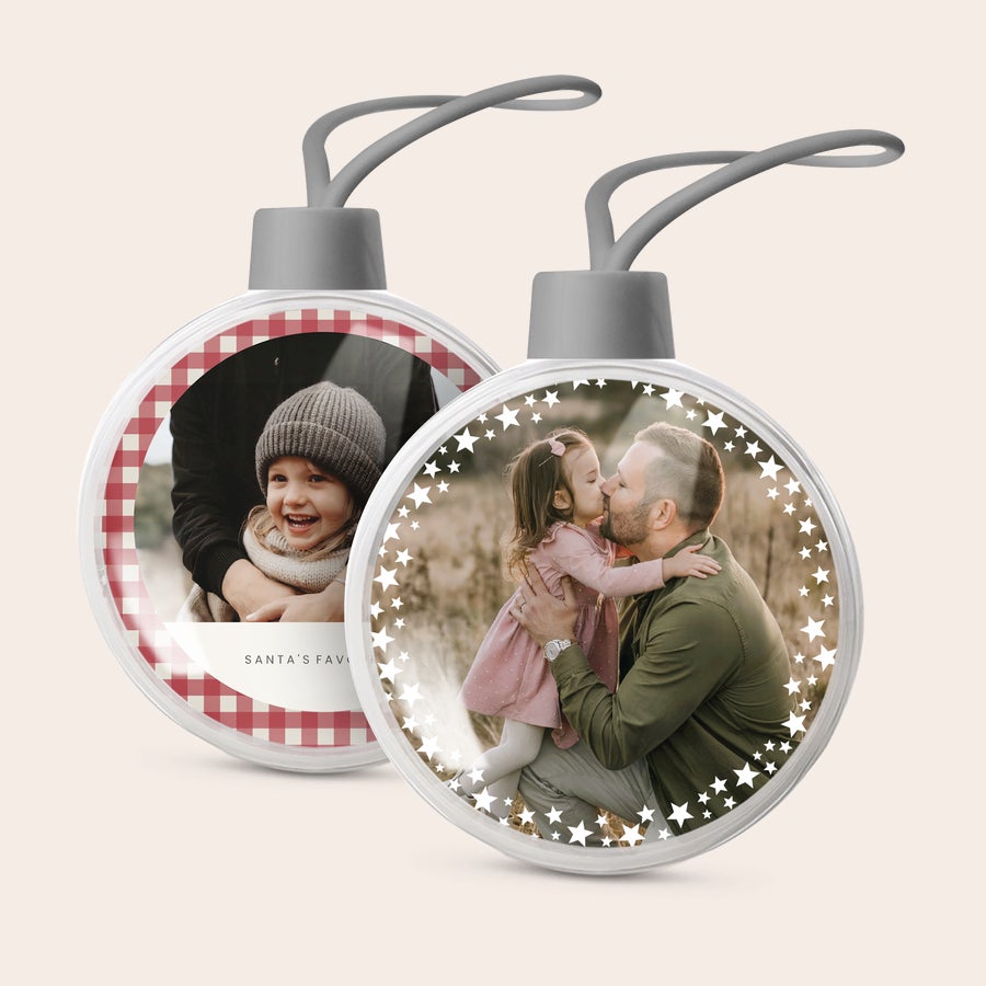 Vánoční koule - transparentní Dvě průhledné vánoční ozdoby s vlastní fotkou. Jedna s dítětem a textem "SANTA'S FAVOURITE", druhá s otcem a dcerou, potištěné.