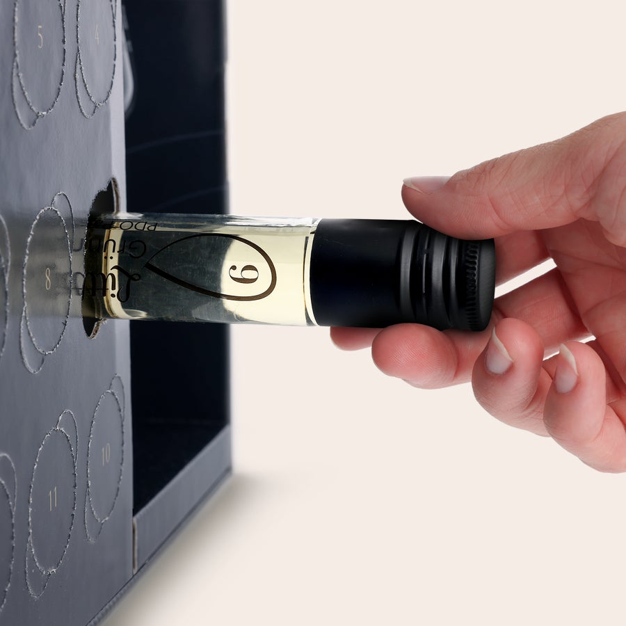 Vin adventskalender - med graverat glas Hand som tar ut ett vinglas med siffran 6 från en vin adventskalender - med graverat glas.