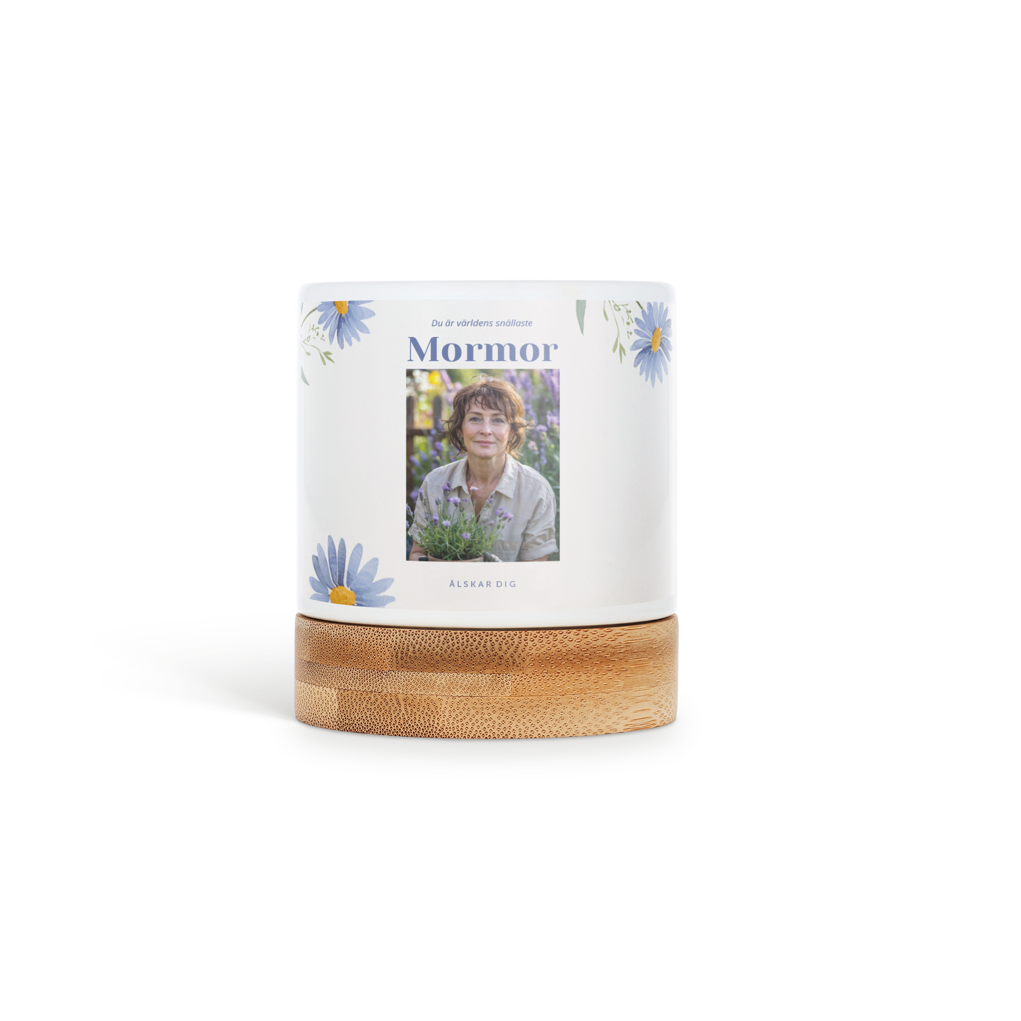 Vit personlig blomkruka med bambuunderlägg, tryckt med en bild av en kvinna och texten "Du är världens snällaste Mormor ÄLSKAR DIG" samt blå blommor.