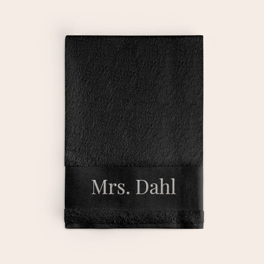 Handduk med Text Svart broderad handduk med vit text Mrs Dahl gör varje badstund personlig.