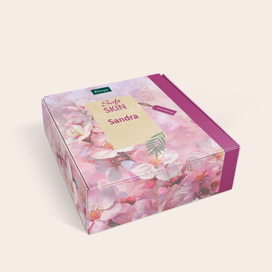 Henkilökohtainen Kneipp Women -lahjarasia - Kneipp design Yksilöllinen Kneipp Soft Skin -lahjasetti, jossa on vaaleanpunainen kirsikankukka-aihe ja nimi Sandra painettuna.