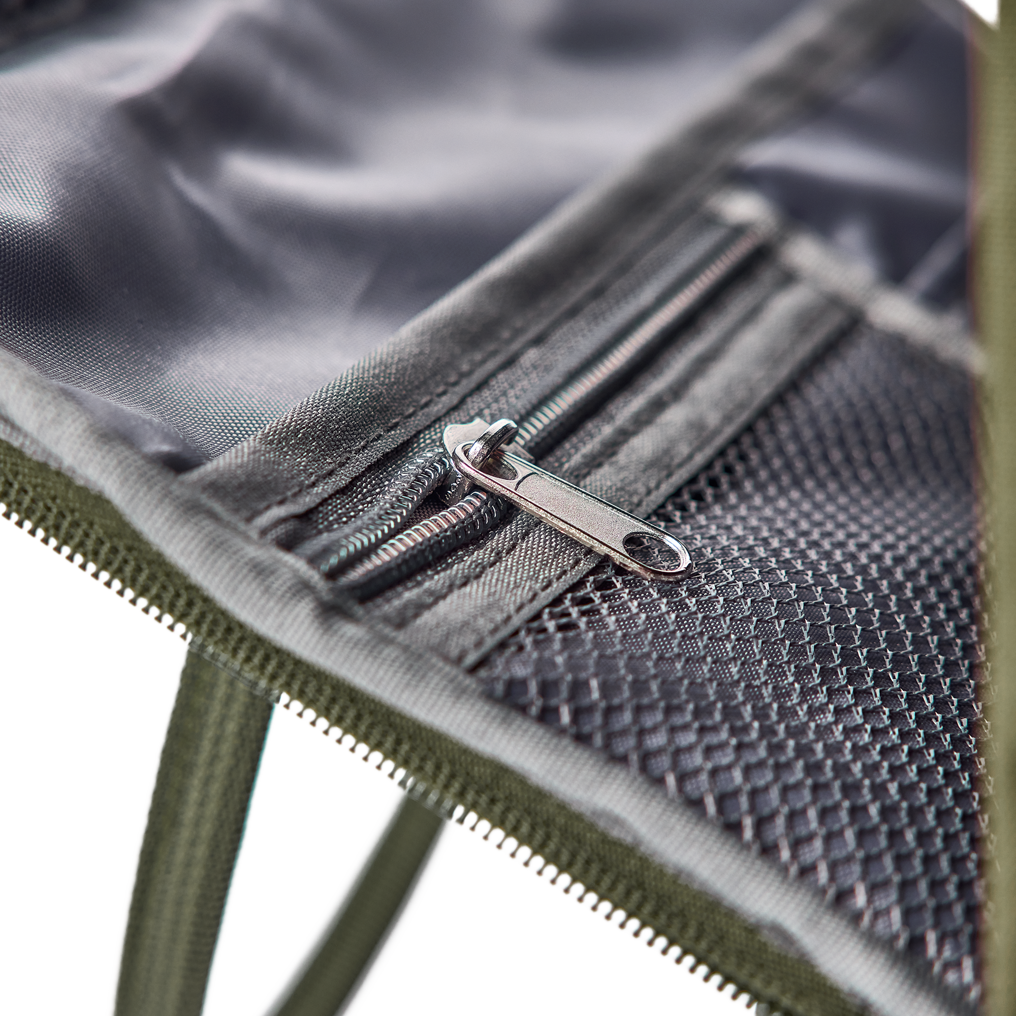 Rucsac personalizat cu numele dorit, un fermoar argintiu și plasă, detaliu din material textil khaki.