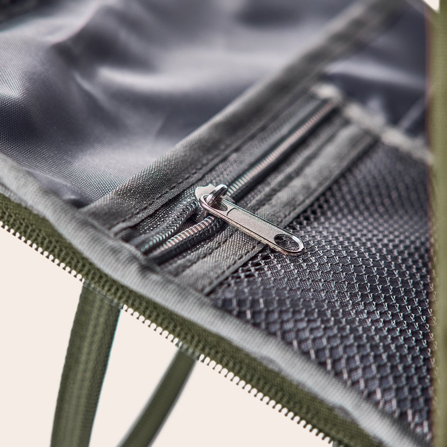 Rucsac cu nume personalizat Rucsac personalizat cu numele dorit, un fermoar argintiu și plasă, detaliu din material textil khaki.