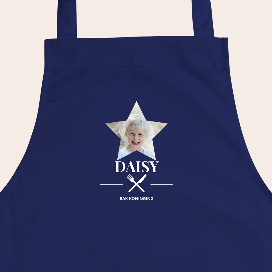 Kinderschort met naam Donkerblauw kinderschort bedrukt met foto van een meisje in stervorm, de naam Daisy en tekst Bak Koningin